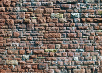a large red and grey old sandstone wall with rough textured surface