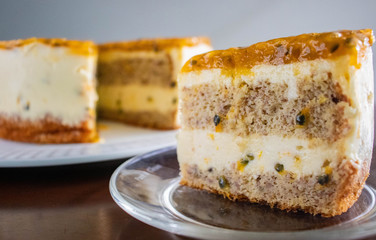 Passion fruit biscuit cake with cream cheese filling and jelly like fruit coulis top, homemade cake with slice on the plate.