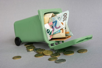 closeup of Euro banknotes and coins in the garbage can