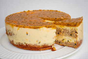 Passion fruit biscuit cake with cream cheese filling and jelly like fruit coulis top, homemade cake with slice on the plate.