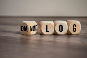 Cubes and dice on wooden background with the german words for dialogue and monologue - dialog und monolog - obrazy, fototapety, plakaty