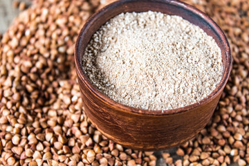 Buckwheat flour in a bowl near the buckwheat grain. A pile of buckwheat flour.