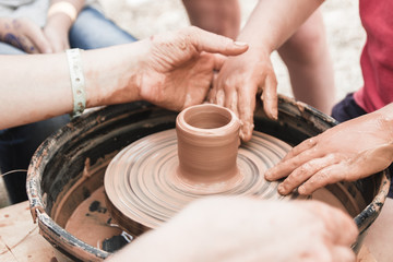 A close up view on ceramic production process on potter's wheel with children. Clay crafts with kids concept.