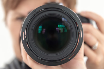 Close up of a DSLR camera lens, blurred hands of woman professional photographer