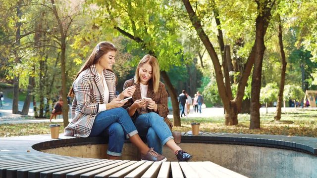 Happy girls browsing social media using smartphones in public park