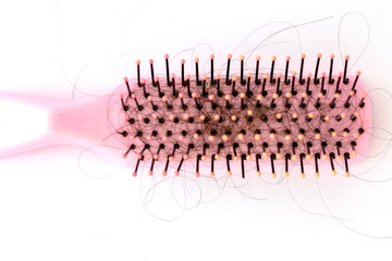 Pink hairbrush on white background. Close-up with long black hair. Hair loss problem. Health care concept