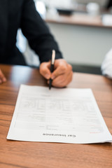 selective focus of man signing car insurance contract