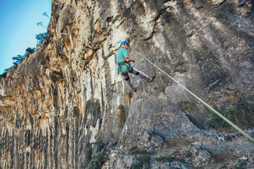 Senior man with a rope climbing on the rock.