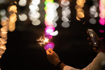 Woman hand with sparkling fireworks stick  at night.