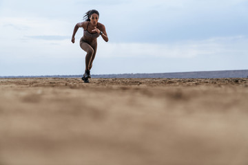Image of serious african american woman in sportswear running by seaside © Drobot Dean