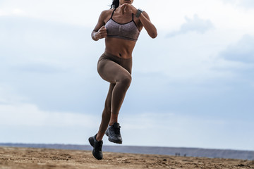 Fototapeta na wymiar Cropped image of african american woman in sportswear running by seaside