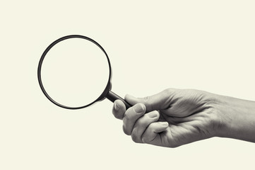 Female hand holding the magnifying glass on isolated background. Black and white image.