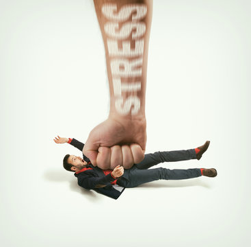 The big human fist with text - stress bring down the man off his feet. Concept of emotional exhaustion, stress. Image.