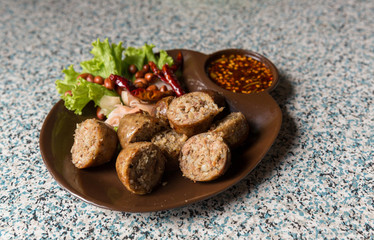 Sausage small circles on the grid-iron grill with smoke over charcoal. Thai sausage, fermented rice with pork sausage served with vegetables.