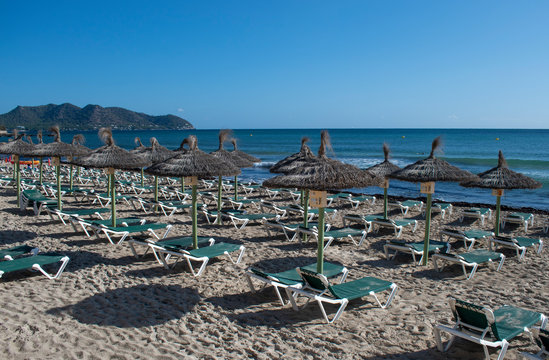 Cala Millor Beach early morning with empty sunbeds and umbrellas awaiting the holidaymakers.
