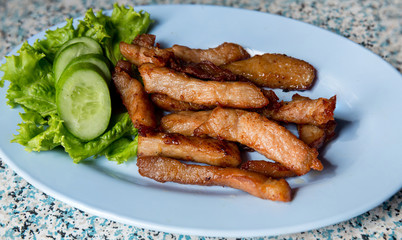 Sliced pork roasted thai style with green leaves salad on rustic plate with cutlery.charcoalboiled pork neck Grill pork Thai style food