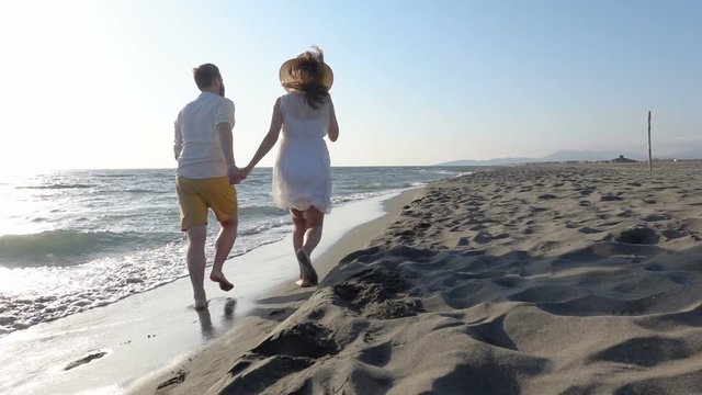 couple having fun running along the beach near the water