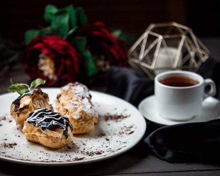 three kind of ekler in the plate served with a cup of tea