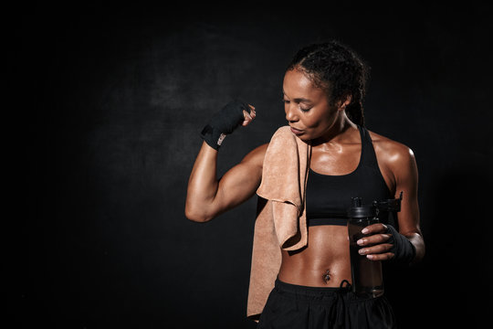 Image of strong african american woman in boxing hand wraps showing her bicep