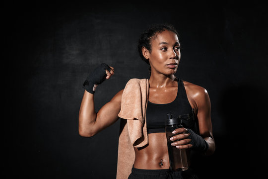 Image of healthy african american woman in boxing hand wraps showing her bicep