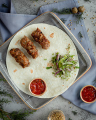 top view of lula kabab with lavash, ketchup and greens