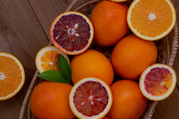 Red and yellow oranges in a basket on a wooden background