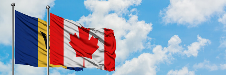 Naklejka premium Barbados and Canada flag waving in the wind against white cloudy blue sky together. Diplomacy concept, international relations.