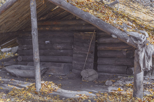 Dugout (or dug-out, pit-house, earth lodge, cellar dug) from logs in autumn forest. Traditional shelter for humans and livestock based on hole  into ground. Natural historical museum of dugouts. Toned