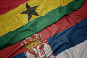 waving colorful flag of serbia and national flag of ghana.