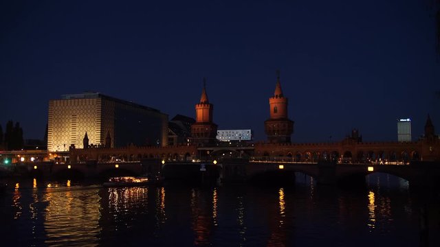Boat at night on river Spree by Oberbaum bridge. Berlin, Germany.
