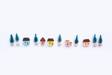 Merry Christmas and Happy Holidays, Miniature house with fir trees on white background.