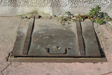 Old rusty metal cover lid for basement entrance on street sidewalk pavement