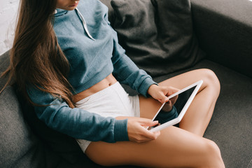 Obraz na płótnie Canvas cropped view of girl in panties using digital tablet on sofa