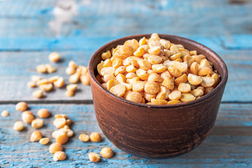 Dry yellow peas in a bowl on old boards. Chipped yellow peas are used for cooking.