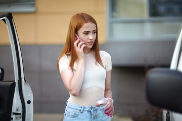 Young girl with red hair stands and smiles on a city street