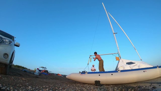 Two men disassemble sailing catamaran