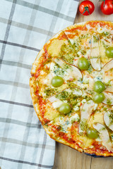 Italian, homemade sliced 4 cheese pizza with pear and grapes red sauce on a wooden table. Top view food with copy space. Flat lay