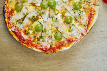 Italian, homemade sliced 4 cheese pizza with pear and grapes red sauce on a wooden table. Top view food with copy space. Flat lay