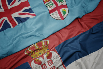 waving colorful flag of serbia and national flag of Fiji .