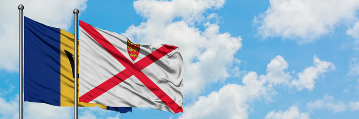 Barbados and Jersey flag waving in the wind against white cloudy blue sky together. Diplomacy concept, international relations.