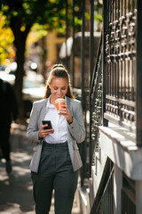 Fototapeta premium Young woman in city using phone on coffee break