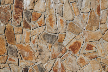 Rusty granite stone wall background. Exterior of a house. Rough industrial surface. Stones of different size.