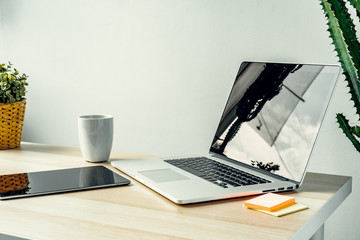 Laptop in a light room on working table with office supplies