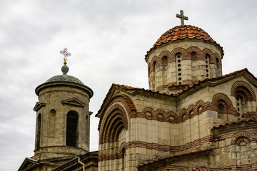 Fototapeta premium Church St. John Baptist, built in 8th century against cloudy sky. Closeup temple building built and Crimean stone. On bell tower and domes church Orthodox crosses.