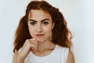 teen girl carefully looks at the camera and holds her chin with her hand