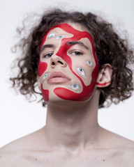 Man studio portrait with makeup for halloween. Abstraction on the face and many eyes.
