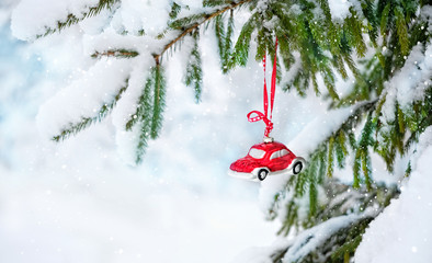 primitive red car toy on snowy Christmas tree. festive Christmas winter season. Christmas and new year holidays concept. soft selective focus