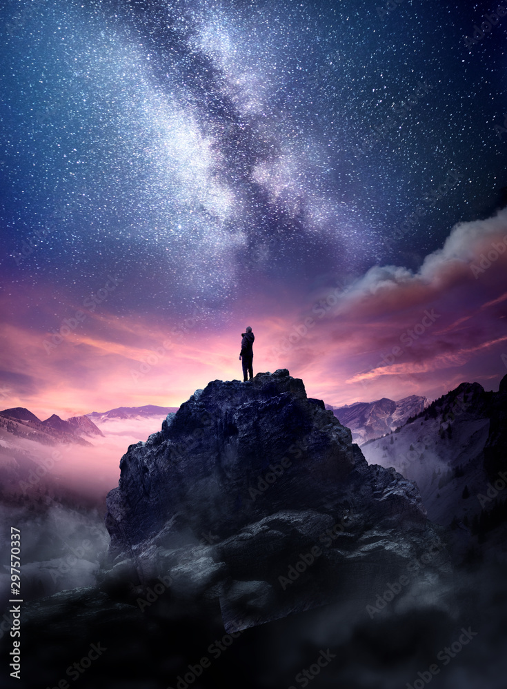 Wall mural night sky long exposure landscape. a man standing on a high rock watching the stars rise into the ni