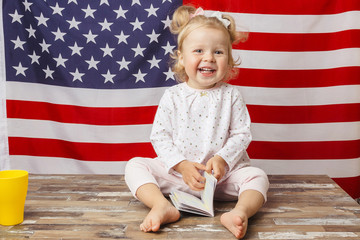 Child with a blue passport in the hand on the American flag background. Studio shoot