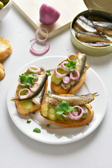 Sandwiches with sprats, marinated cucumber and onion